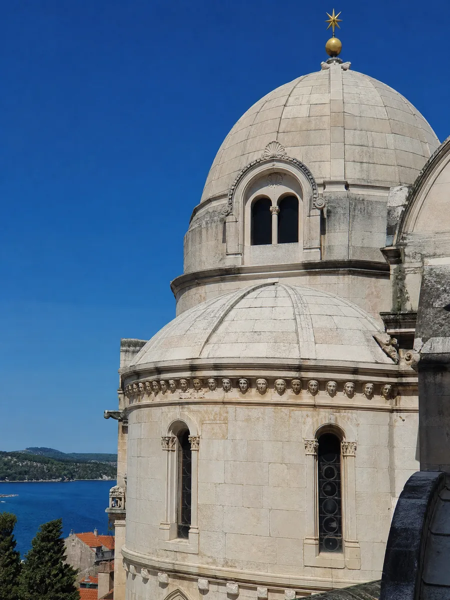 The stone dome and apse of the Cathedral of St James in Šibenik against a blue sky